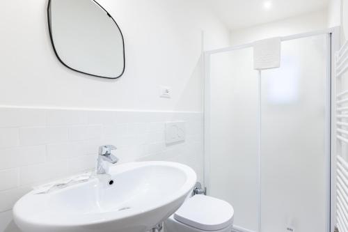 W białej łazience znajduje się umywalka i lustro. w obiekcie Simon, Bologna by Short Holidays w Bolonii