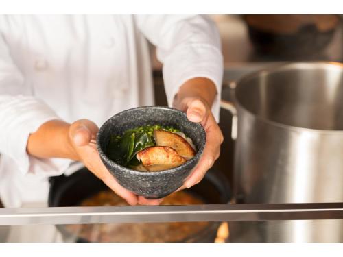a chef holding a bowl of food in the oven at Villa Fontaine Grand Haneda Airport in Tokyo