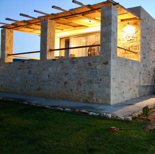 a house with a stone wall and a wooden roof at Alagni Cretan Resort in Stíronas