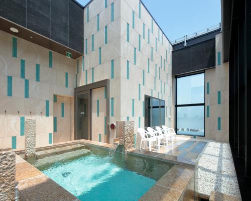 a house with a swimming pool with chairs in it at Candeo Hotels Kumamoto Shinshigai in Kumamoto