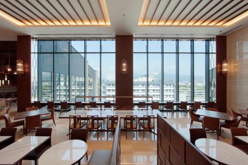 a restaurant with tables and chairs and large windows at Candeo Hotels Kumamoto Shinshigai in Kumamoto
