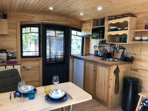 a kitchen with a table in a tiny house at Roulotte Gîtes O bien-être massage Spa Séjour bien-être en hébergement insolite roulotte Karantez ou en gîtes Melon ou Yock à 800 m des plages Maison d'hôte Drogou in Porspoder