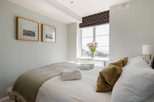 a white bedroom with a large bed with a window at Spacious and luxe two king bedroom sea-view apt in Brighton & Hove