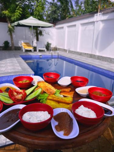 a table topped with bowls of food next to a pool at Qafqaz Fountain House in Gabala