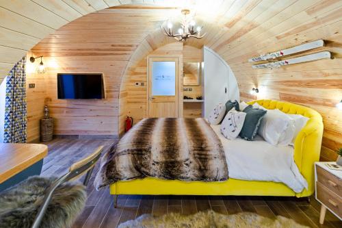 a bedroom with a yellow bed in a room with wooden walls at Cliff Stud Retreat - Luxury lodges and cosy cottages in Helmsley