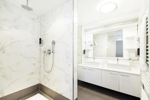 a white bathroom with two sinks and a shower at Hotel am Berliner Platz in Langenfeld