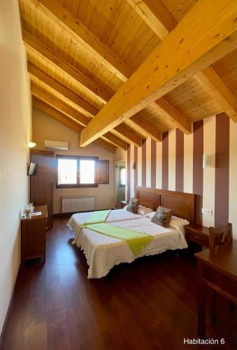 a bedroom with a large bed in a room with wooden ceilings at La Posada de Pesquera in Pesquera de Duero