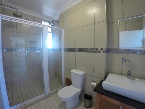a bathroom with a shower and a toilet and a sink at 53 Sea Lodge Umhlanga Rocks in Durban