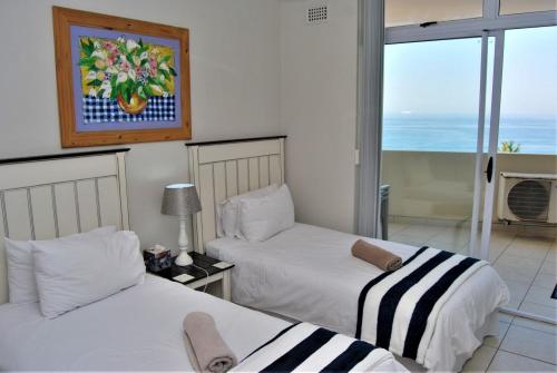 two beds in a room with a view of the ocean at 53 Sea Lodge Umhlanga Rocks in Durban