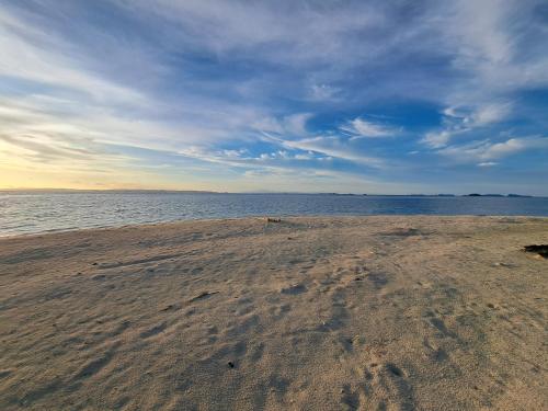 a sandy beach with the ocean on a cloudy day at Raja Ampat Jousuba Homestay in Minyaifuin