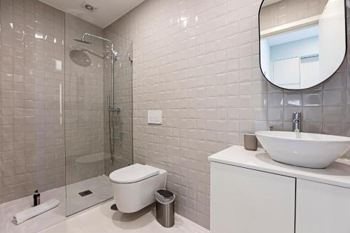 een badkamer met een toilet, een wastafel en een spiegel bij 31 Janeiro 157 - Delightful 1BR Flat w/ AC & Balcony by LovelyStay in Porto