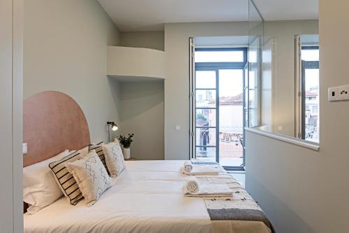 een slaapkamer met een bed en een groot raam bij 31 Janeiro 157 - Delightful 1BR Flat w/ AC & Balcony by LovelyStay in Porto