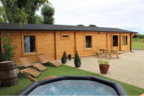 a log cabin with chairs and a picnic table at Stunning 5-Bed Cabin in Ashton Under Hill in Evesham