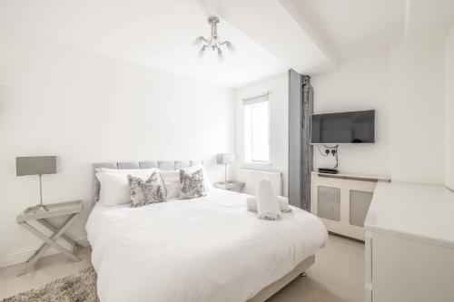 ein weißes Schlafzimmer mit einem weißen Bett und einem TV in der Unterkunft Windsor Castle & High Street 2 min walk in Windsor