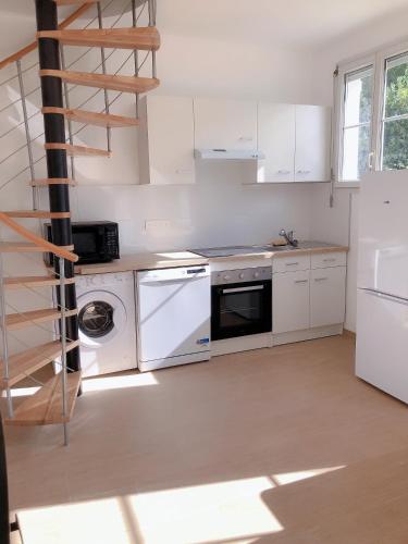une cuisine avec des appareils électroménagers blancs et un escalier en colimaçon dans l'établissement petite maison avec jardin dans banlieue de Paris, à Cormeilles-en-Parisis