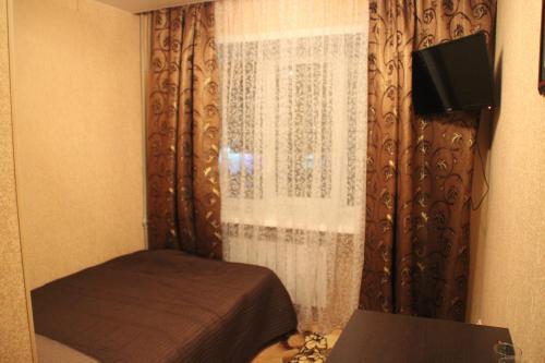 a bedroom with a bed and a window with a television at Hotel Lyuks in Arzamas
