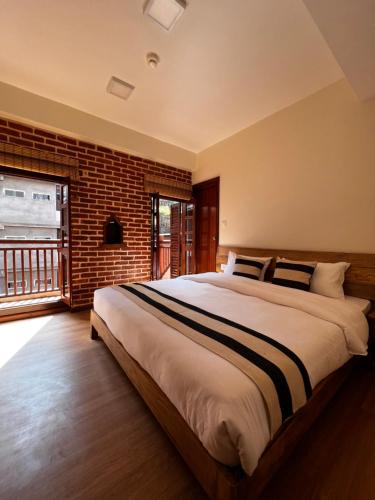ein Schlafzimmer mit einem großen Bett und einer Ziegelwand in der Unterkunft KGH Patan in Pātan
