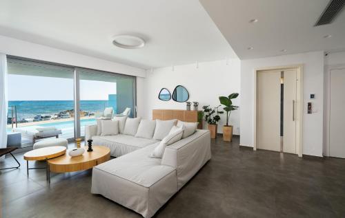 Sala de estar con sofá blanco y vistas al océano en Dia's Blue Villa, en Gournes