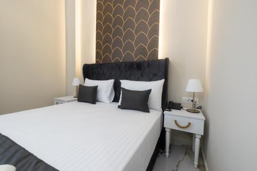 a bedroom with a white bed with a black headboard at Modern Revival Luxury Hotel in Thessaloniki