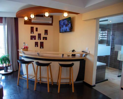 a kitchen with a bar with stools and a shower at Hotel La Villette in Antananarivo