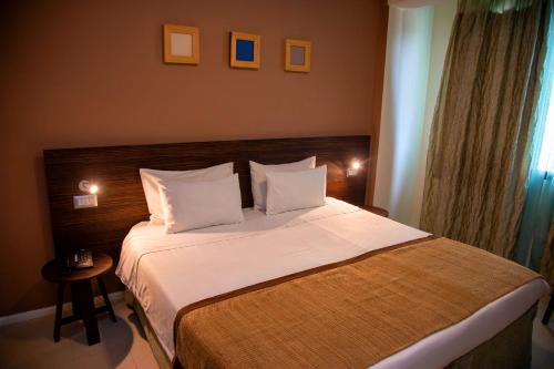 a bedroom with a large bed with white sheets and pillows at Hotel La Villette in Antananarivo