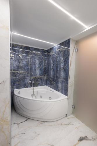 a white bath tub in a bathroom with blue tiles at Modern Revival Luxury Hotel in Thessaloniki