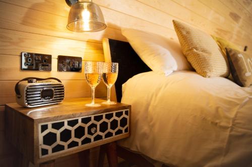 a bedroom with a bed and two glasses of champagne at Cliff Stud Retreat - Luxury lodges and cosy cottages in Helmsley