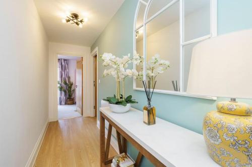 a hallway with a table with flowers in a vase at Darlington - 2 Bedroom Luxury Apartment by Mint Stays in Bristol