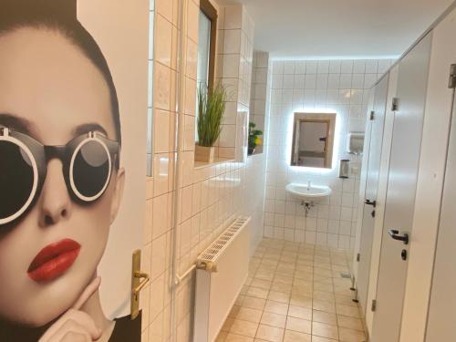 a painting of a woman wearing sunglasses in a bathroom at Hotel Bielatal in Olbernhau