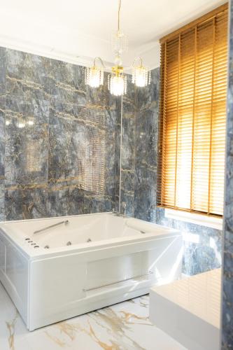 a white bath tub in a bathroom with marble walls at Modern Revival Luxury Hotel in Thessaloniki