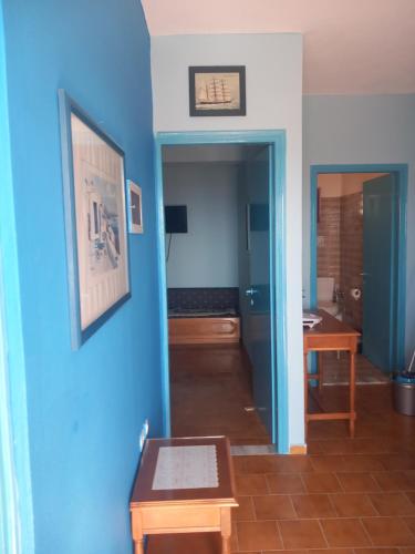 a room with a blue wall and a table and a room with a desk at Zafira Studios in Kefalos