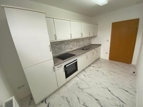 a kitchen with white cabinets and a marble floor at Hotel Bielatal in Olbernhau