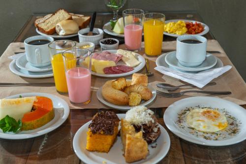 a table topped with plates of breakfast foods and drinks at Pousada UpSerra in Urubici