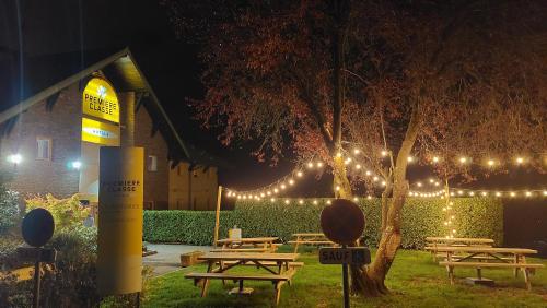 un groupe de tables de pique-nique dans un parc éclairé dans l'établissement Premiere Classe Annecy Cran-Gevrier, à Annecy