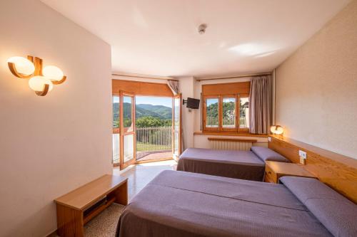 a hotel room with two beds and a balcony at Hotel Restaurante La Glorieta in La Seu d'Urgell