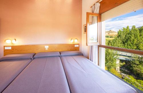 a bed in a room with a large window at Hotel Restaurante La Glorieta in La Seu d'Urgell