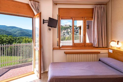 a bedroom with a bed and a balcony with a view at Hotel Restaurante La Glorieta in La Seu d'Urgell