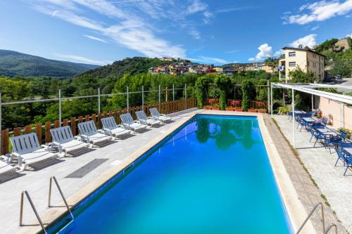 a swimming pool with chairs and a mountain in the background at Hotel Restaurante La Glorieta in La Seu d'Urgell
