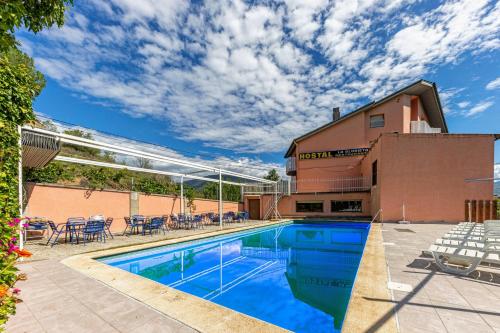 a swimming pool with tables and chairs next to a building at Hotel Restaurante La Glorieta in La Seu d'Urgell