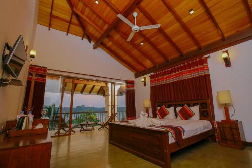 a bedroom with a large bed and a balcony at Diya Dahara Lake Resort in Tissamaharama