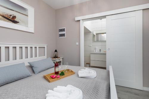 a white room with a bed with a tray of towels at Seaside Apartment with Parking - Międzyzdroje Dąbrówki by Renters in Międzyzdroje