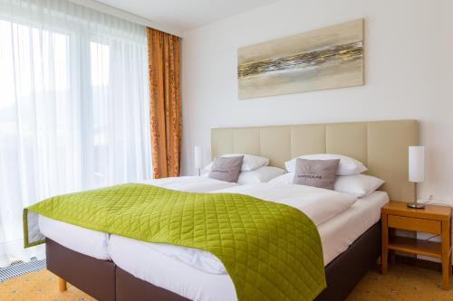 a bedroom with a large bed with a green blanket at Der Trattner - Hotel Trattnerhof & Hotel Schöcklblick in Semriach