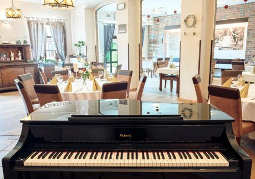 een piano in een kamer met een restaurant bij Stara Szkoła Boutique Hotel in Wronki