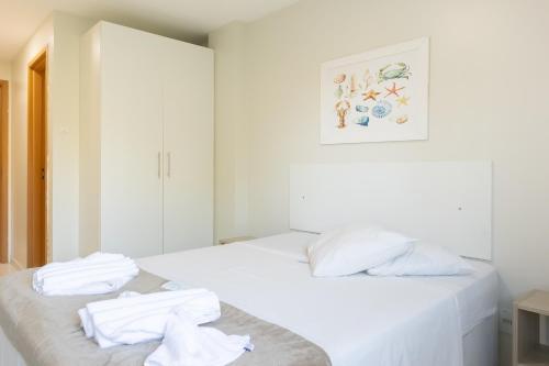 um quarto branco com duas camas com toalhas em Aquarius Residence em Porto de Galinhas