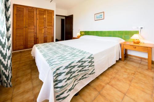 a bedroom with a large bed and a wooden table at Apartamentos Sa Cornisa in Cala Morell