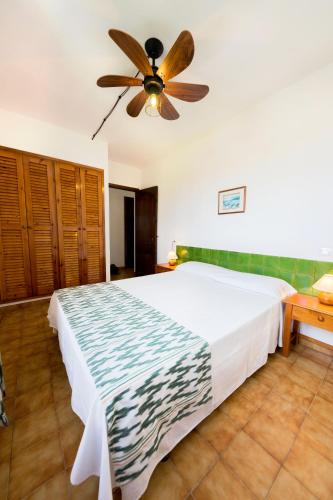 a bedroom with a large bed with a ceiling fan at Apartamentos Sa Cornisa in Cala Morell