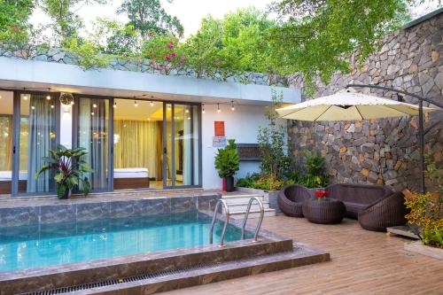a house with a swimming pool and an umbrella at Villa Đỗ Quyên F5B in Ngọc Quang
