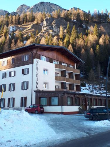 Un gran edificio con coches aparcados en un estacionamiento. en Hotel Sorapiss, en Misurina