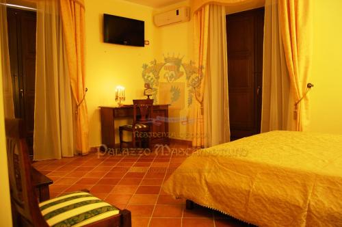 1 dormitorio con 1 cama y TV en la pared en Palazzo Mascambruno en Cariati