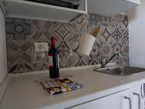 eine Küchentheke mit einer Flasche Wein und zwei Gläsern in der Unterkunft Il palmento di Beppe in Santa Tecla